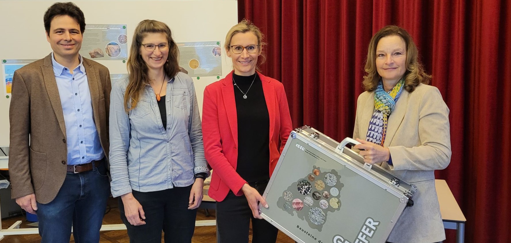 Vier Personen stehen nebeneinander. Eine Frau hält den GeoKoffer des ISTE.